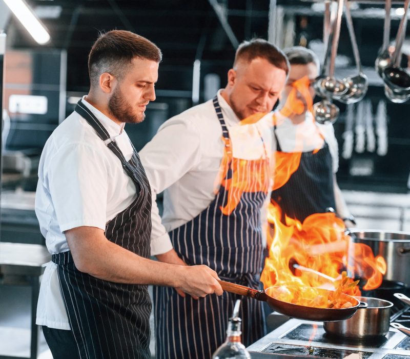 flaming-the-meal-on-frying-pan-kitchen-workers-is-together-preparing-the-food.jpg